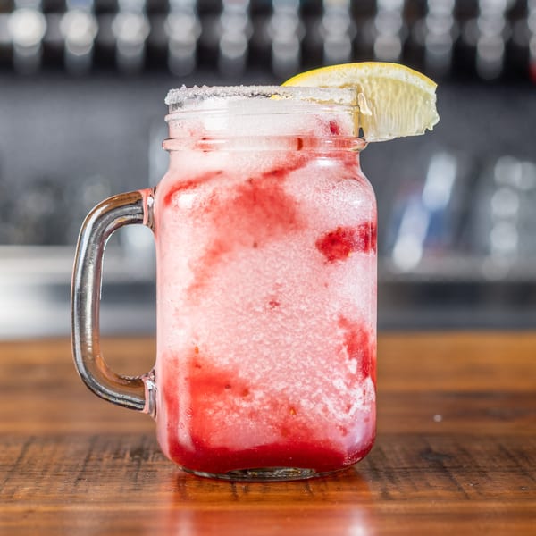 A Wicked Peel Pizza strawberry frozen drink in a mason jar with a lemon wedge.